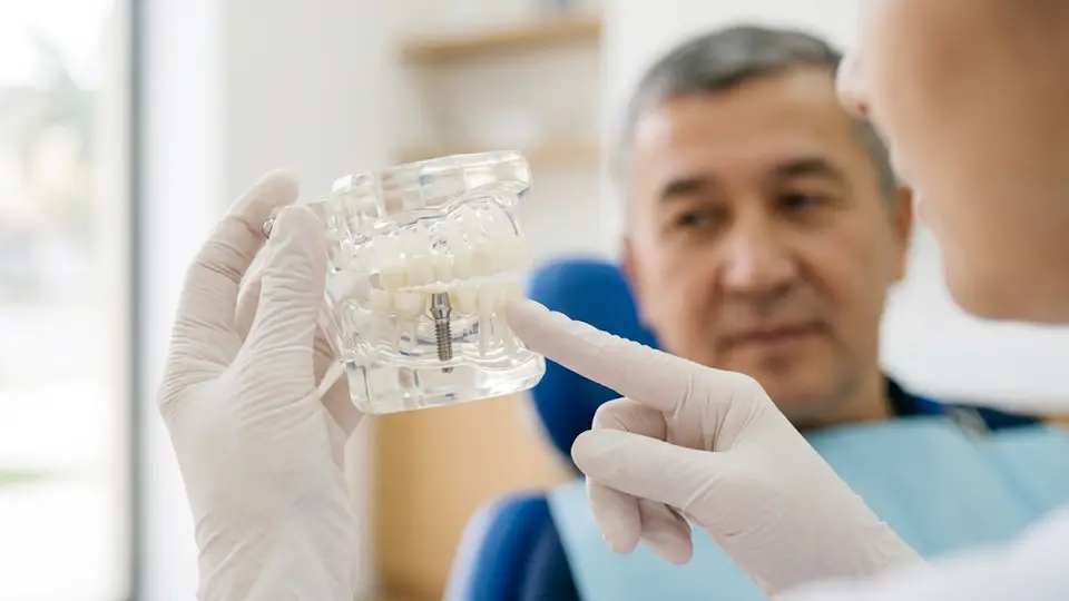 Shifokor implant modelini koʻrsatmoqda
